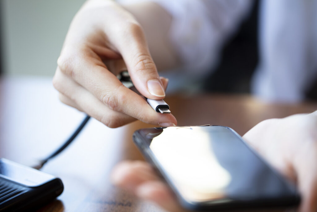 Woman hands plugging in a charging cord to smart phone at home