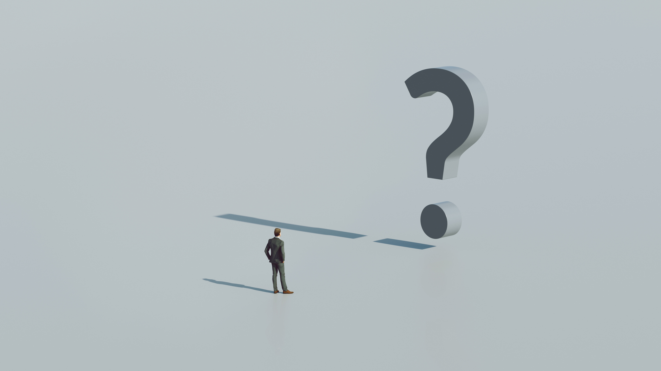 Concept image with man in suit standing in front of a giant question mark. The question mark casts a shadow formed as an exclamation mark.